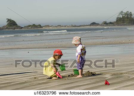 Stock Photograph - Children play in sand on beach, Chesterman Beach, Tofino, British Columbia, Canada.. Fotosearch
