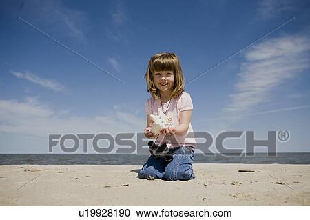 Stock Image - Four year old girl shows shell at the beach, Grand Beach Provincial Park, Manitoba, Canada. Fotosearch