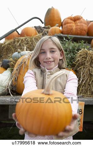 Stock Photo - Girl holding organic pumpkin toward camera, Ladner, British Columbia, Canada. Fotosearch