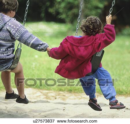 Stock Photo - Kids hold hands while playing on swing, Hornby Island, BC Canada. Fotosearch