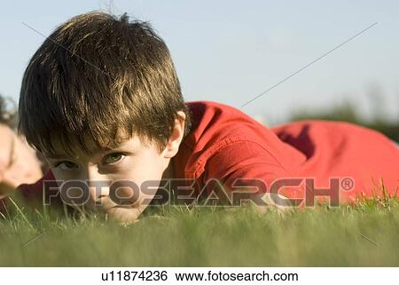 Stock Photograph - Six year old boy looks up from laying on grass, Assiniboine Park, Winnipeg, Canada. Fotosearch