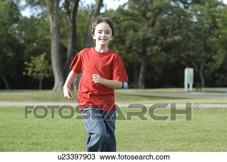 Stock Image - Six year old boy running toward camera, Assiniboine Park, Winnipeg, Canada. Fotosearch