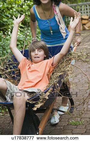 Teenage Siblings Playing With a Wheelbarrow. West Vancouver, BC. View Large Photo Image Stock Photo - Teenage Siblings Playing With a Wheelbarrow. West Vancouver, BC.. Fotosearch