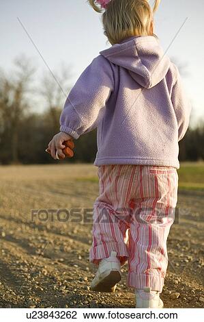 Stock Image - Three year old girl on bare field, Saskatchewan, Canada. Fotosearch
