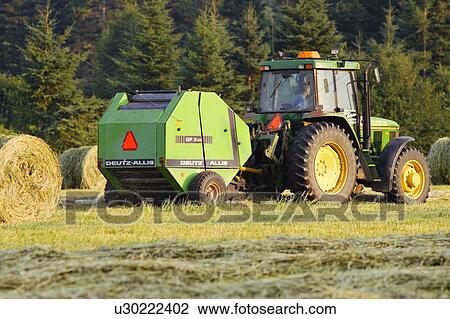Stock Image - Farmer cutting hay in field, Bas-Saint-Laurent region, Quebec, Canada. Fotosearch