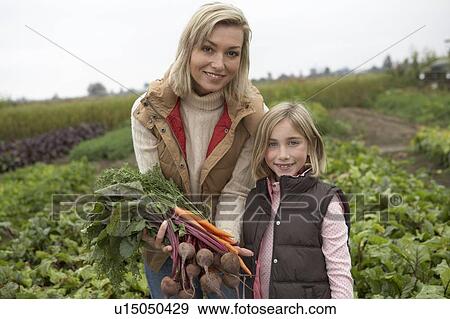 Stock Photo - Mother and daughter at an organic farm with fresh vegetables, Ladner, British Columbia, Canada. Fotosearch