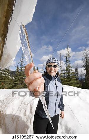 A Woman Grabs An Icicle From The Roof Of A Winter Cabin Silver