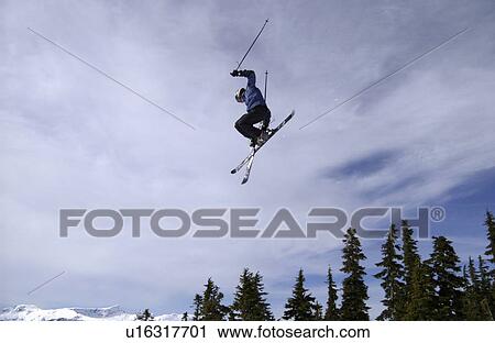 Stock Image - Man (20-25) jumping through the air on skis. Mount Washington Alpine Resort, Courtenay, BC, Canada. Fotosearch