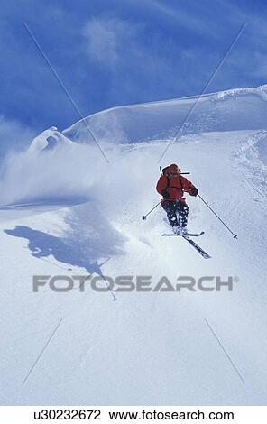 Stock Image - Young man catches air while skiing at Mica Heliskiing, Fernie, British Columbia, Canada.. Fotosearch