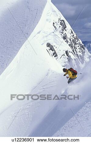 Stock Image - Young man skiing fresh powder on steep slope at Island Lake Resort, Fernie, British Columbia, Canada.. Fotosearch