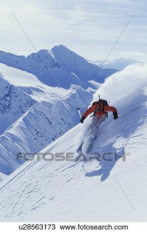 Stock Image - Young man skiing on steep slope at Mica Heliskiing, Mica Creek, British Columbia, Canada.. Fotosearch