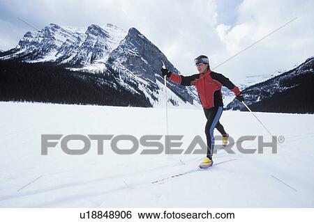 Stock Photograph - Young woman cross country skiing on Lake Louise, Banff National Park, Alberta, Canada. Fotosearch