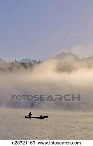 Stock Photo - Canoeist on Alta Lake, with mountains and mist. Fotosearch