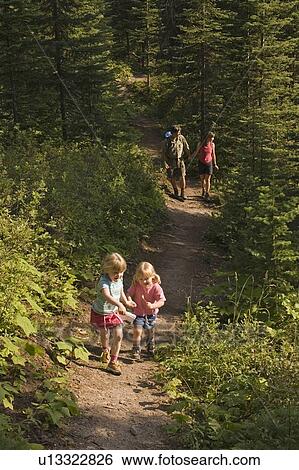 Stock Photograph - Children run ahead of parents during hike on trail at Island Lake Resort, Fernie, British Columbia, Canada.. Fotosearch
