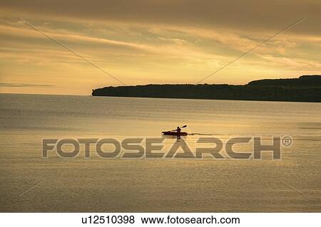 Stock Photo - Distant kayak on Lake Superior, sunset. Fotosearch