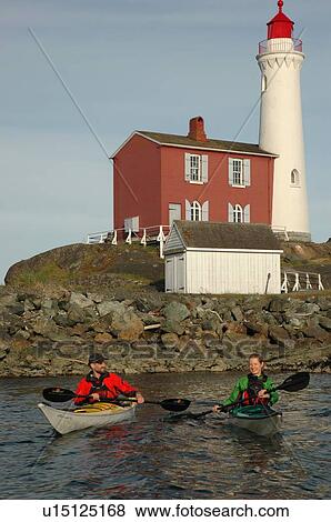 Stock Photo - Man (30-35) and woman (25-30) kayaking in front of a lighthouse, Esquimalt, BC. Fotosearch