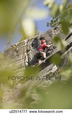 Stock Photo - Mid-age man climbing up 5. 8 route at Stone Hills near Rexford, Montana, USA. Fotosearch