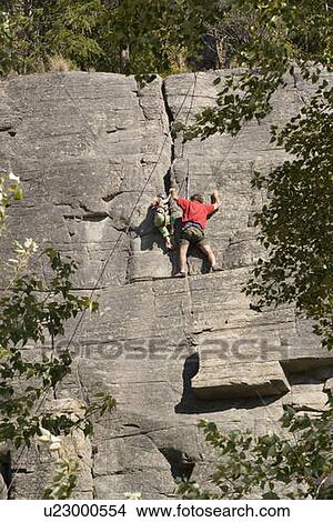 Picture - Mid-age man climbing with daughter (age 5) up granite cliff at Stone Hills near Rexford, Montana, USA. Fotosearch