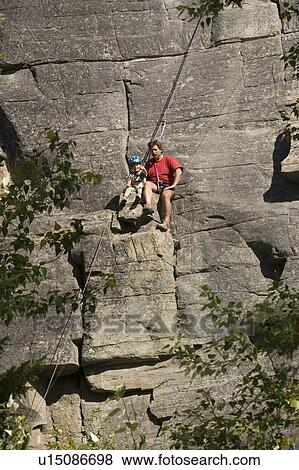 Mid-age man climbing with daughter (age 5) up granite cliff at Stone Hills near Rexford, Montana, USA View Large Photo Image Stock Photo - Mid-age man climbing with daughter (age 5) up granite cliff at Stone Hills near Rexford, Montana, USA. Fotosearch