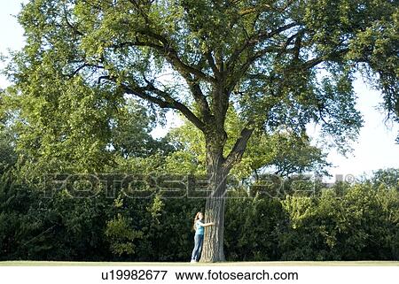 Twelve year old girl hugging trunk of large tree in Assiniboine Park, Winnipeg, Canada View Large Photo Image Stock Photo - Twelve year old girl hugging trunk of large tree in Assiniboine Park, Winnipeg, Canada. Fotosearch