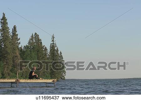 Woman seated on dock by lake, Clear Lake, Riding Mountain National Park, Manitoba, Canada View Large Photo Image Stock Photo - Woman seated on dock by lake, Clear Lake, Riding Mountain National Park, Manitoba, Canada. Fotosearch