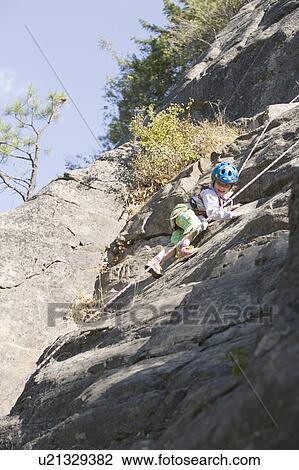 Stock Image - Young girl (age 5) climbing on granite cliff at Stone Hills near Rexford, Montana, USA. Fotosearch