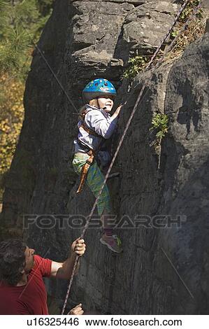 Young girl (age 5) climbing on granite cliff while father belays and watches, Stone Hills near Rexford, Montana, USA View Large Photo Image Stock Photograph - Young girl (age 5) climbing on granite cliff while father belays and watches, Stone Hills near Rexford, Montana, USA. Fotosearch