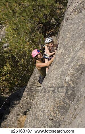 Young woman climbing with daughter (age 7) up granite cliff at Stone Hills near Rexford, Montana, USA View Large Photo Image Stock Photo - Young woman climbing with daughter (age 7) up granite cliff at Stone Hills near Rexford, Montana, USA. Fotosearch