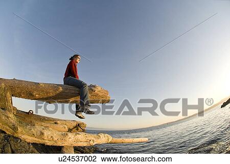 Stock Image - A woman enjoys the sunset on Victoria BC's waterfront. Fotosearch