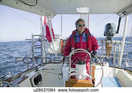 Picture - Man at the helm of a sailboat off the coast of California near San Francisco. Fotosearch