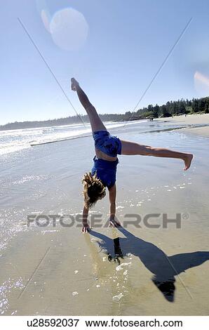 Stock Photo - Pre-teen girl performing cartwheel on beach, Vancouver Island, Canada. Fotosearch