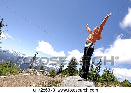 Stock Image - Teen girl with arms open over mountains, Vancouver Island, B. C.. Fotosearch