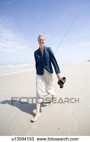 Stock Image - Woman (35) walking on the beach, Jacksonville, Florida. Fotosearch