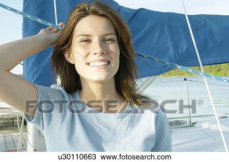Stock Image - Young woman wearing a hemp shirt on sail boat, Clear Lake, Riding Mountain National Park, Manitoba, Canada. Fotosearch