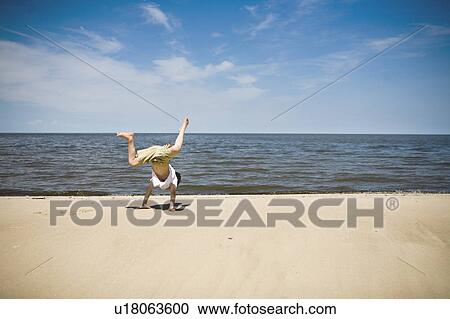 Stock Image - Boy (7) tries to do a cartwheel, Grand Beach Provincial Park, Manitoba, Canada. Fotosearch