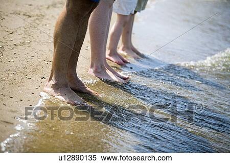 Stock Photography - Line of bare feet at shoreline, Grand Beach Provincial Park, Manitoba, Canada. Fotosearch