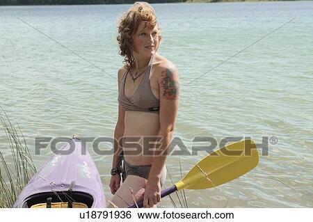 Stock Photograph - Tattooed woman beside kayak, Lake Katherine, Riding Mountain National Park, Manitoba, Canada. Fotosearch