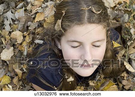 Stock Photograph - Teen girl covered in leaves, Winnipeg, Canada. Fotosearch
