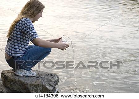 Stock Photograph - Twelve year old girl pouring water sample beside Assiniboine River, Winnipeg, Canada. Fotosearch