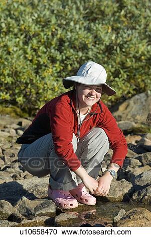 Stock Image - Woman (20-25) by an alpine creek; Canada, Alberta, Jasper National Park, Skyline Trail. Fotosearch