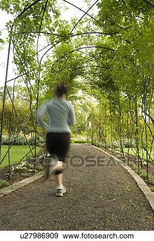 Woman (20-25) jogging through a garden; Canada, British Columbia, Victoria View Large Photo Image Stock Photo - Woman (20-25) jogging through a garden; Canada, British Columbia, Victoria. Fotosearch