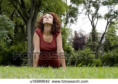 Stock Image - Woman in the park stretches her body upward, Munson Park, Winnipeg, Canada. Fotosearch