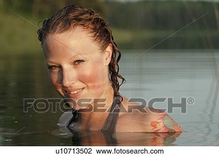 Stock Image - Woman with head and shoulders above water of lake, Lake Katherine, Riding Mountain National Park, Manitoba, Canada. Fotosearch