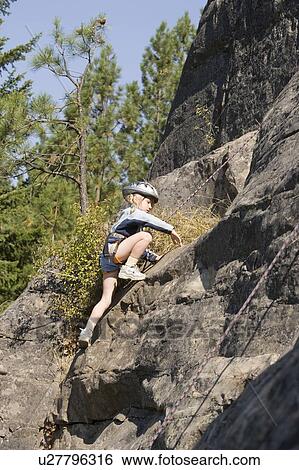 Stock Photograph - Young girl (age 7) climbing on granite cliff at Stone Hills near Rexford, Montana, USA. Fotosearch