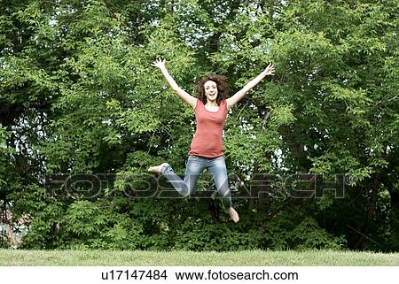 Picture - Young woman in mid jump in park, Munson Park, Winnipeg, Canada. Fotosearch