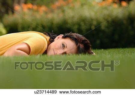 Young woman lying on grass, Regina, Saskatchewan View Large Photo Image Stock Photo - Young woman lying on grass, Regina, Saskatchewan. Fotosearch