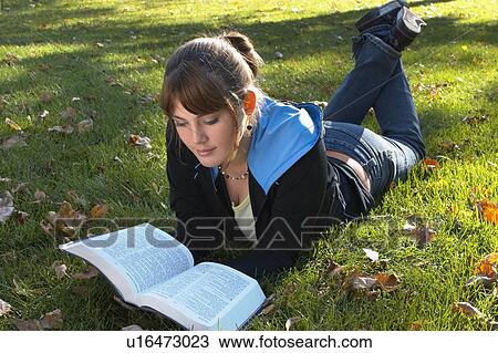 Stock Image - Young woman reading Bible outdoors, Brantford, Ontario. Fotosearch