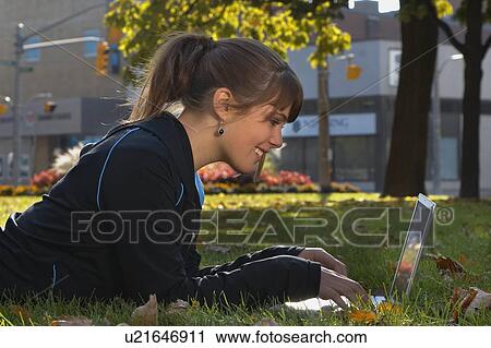 Stock Image - Young woman using laptop outdoors, Brantford, Ontario. Fotosearch