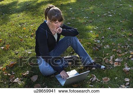 Stock Image - Young woman using laptop outdoors, Brantford, Ontario. Fotosearch