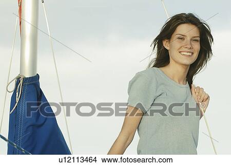 Picture - Young woman wearing hemp shirt holds rope on sailboat, Clear Lake, Riding Mountain National Park, Manitoba, Canada. Fotosearch